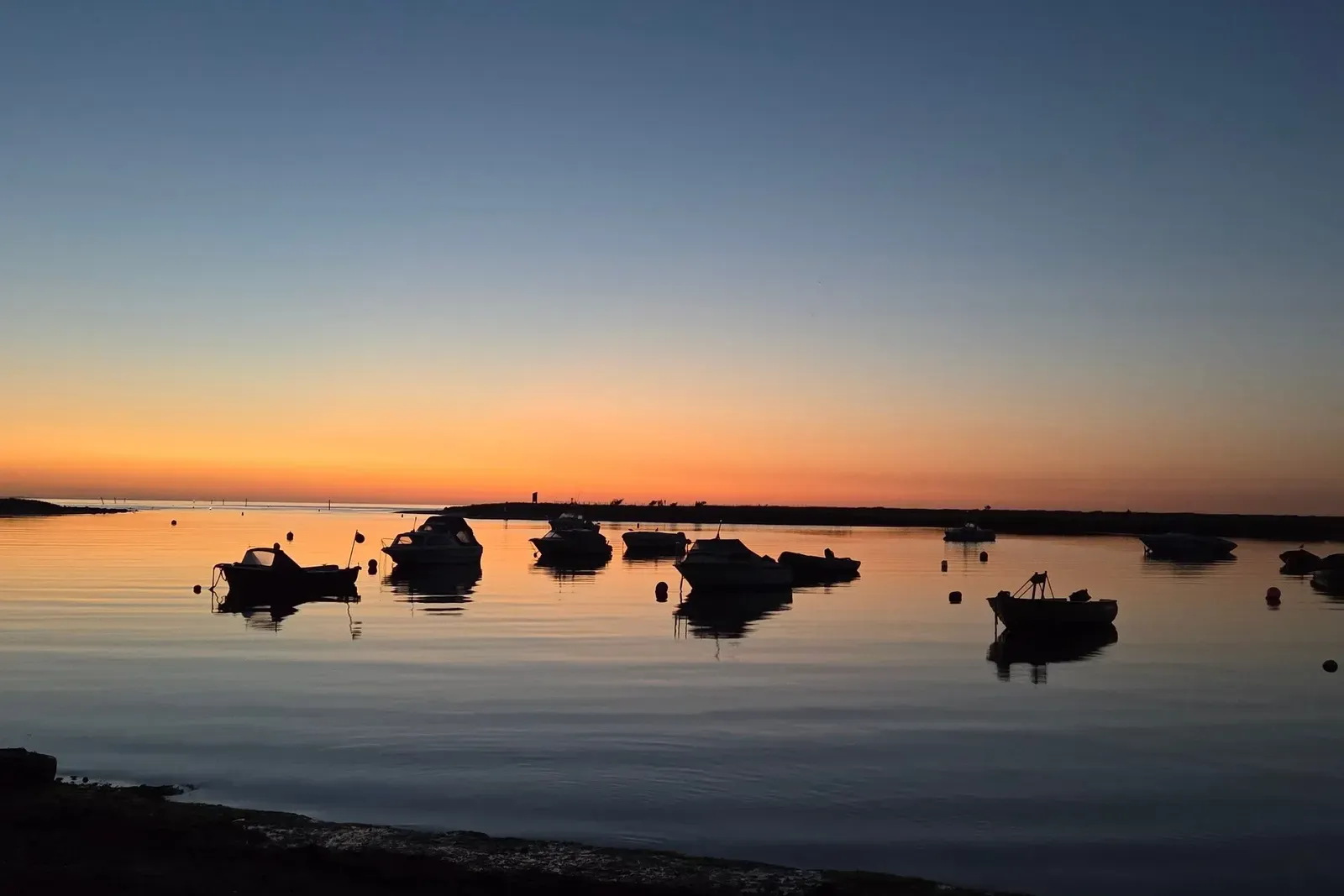 Boote liegen bei Sonnenuntergang an einem Steg im Hafen.