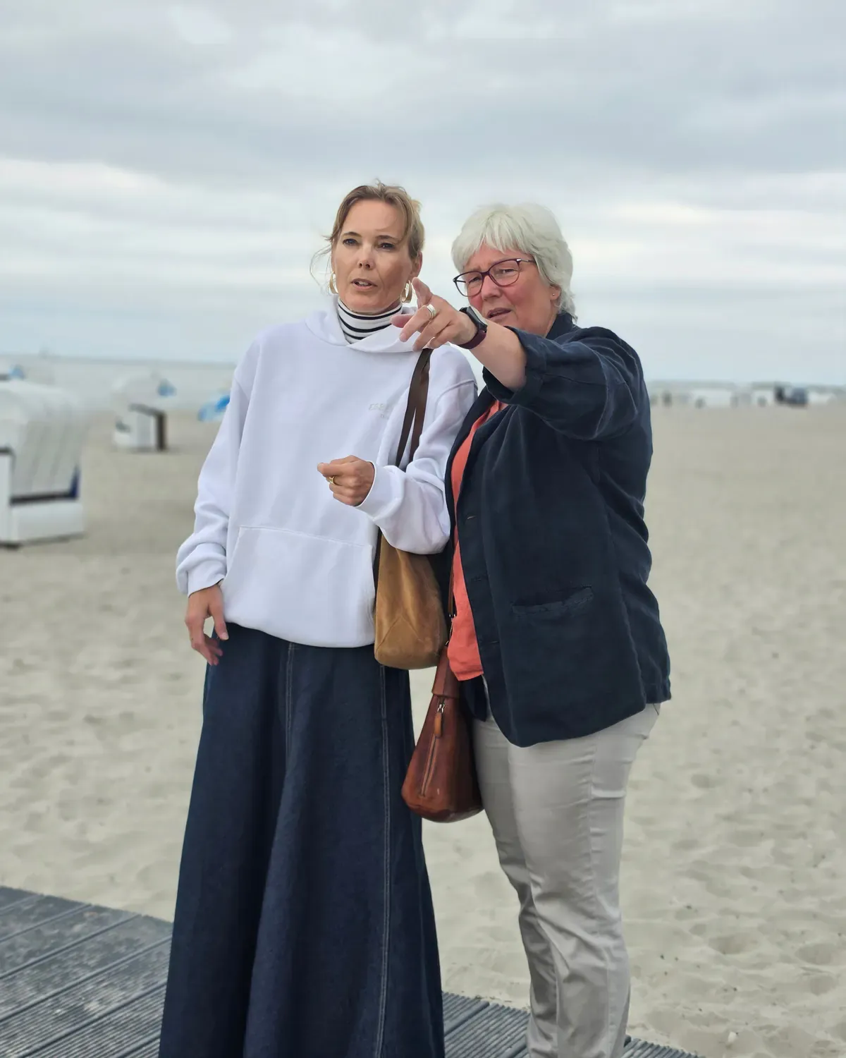 Inken Kuhn und eine Frau stehen am Ostseestrand, Inken zeigt auf etwas in der Ferne.